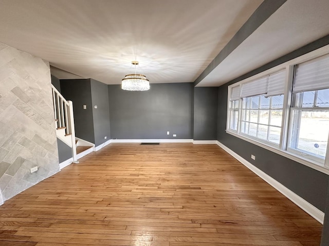 unfurnished dining area featuring hardwood / wood-style floors and a notable chandelier