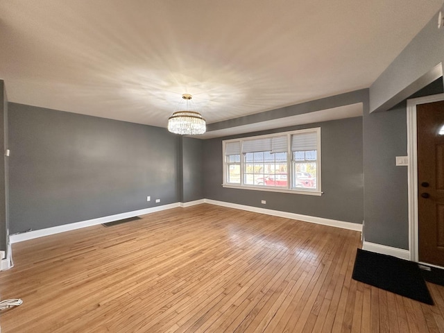 spare room featuring hardwood / wood-style floors and an inviting chandelier