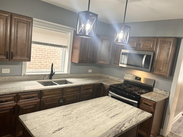 kitchen featuring pendant lighting, sink, dark brown cabinetry, light stone counters, and stainless steel appliances