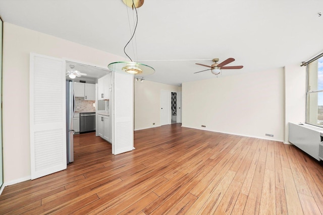 unfurnished living room featuring light hardwood / wood-style flooring, radiator heating unit, and ceiling fan