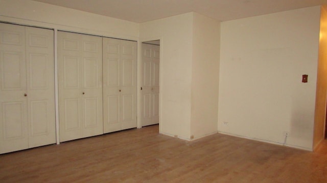 unfurnished bedroom featuring two closets and light hardwood / wood-style floors