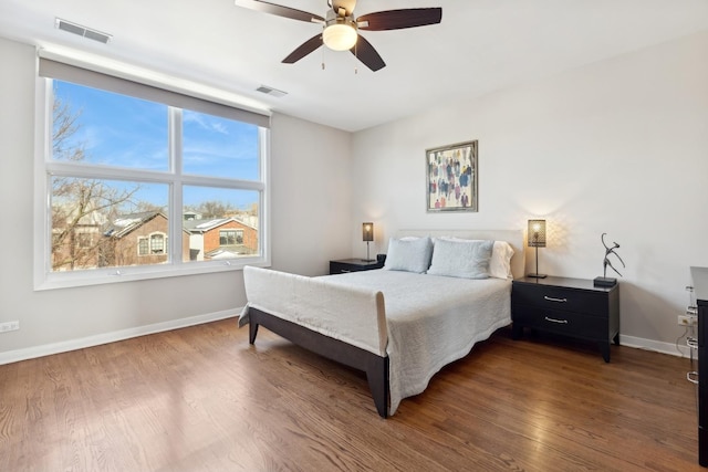 bedroom with dark wood-style floors, visible vents, and baseboards