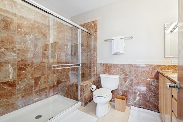 bathroom featuring toilet, vanity, tile walls, tile patterned floors, and a stall shower