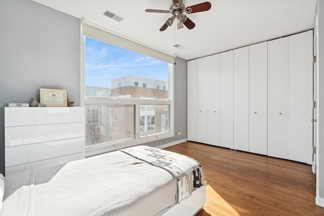 bedroom featuring ceiling fan, wood finished floors, and visible vents