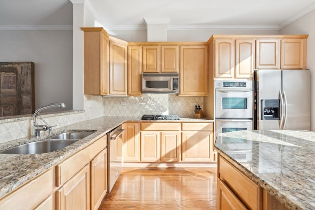 kitchen featuring stainless steel appliances, a sink, ornamental molding, and light brown cabinetry