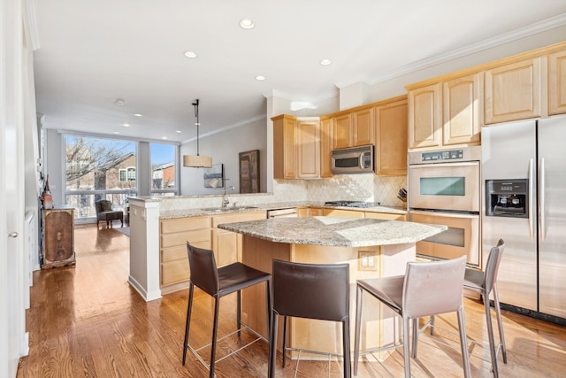 kitchen featuring a peninsula, appliances with stainless steel finishes, light brown cabinets, and tasteful backsplash