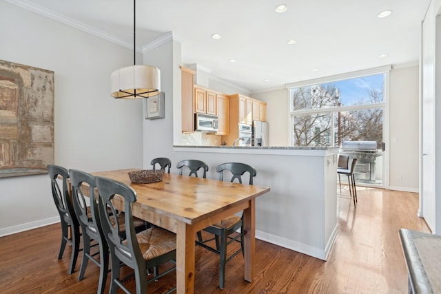 dining room with light wood-style flooring, ornamental molding, baseboards, and recessed lighting