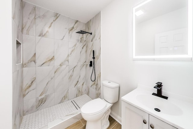 bathroom featuring vanity, toilet, hardwood / wood-style floors, and a tile shower