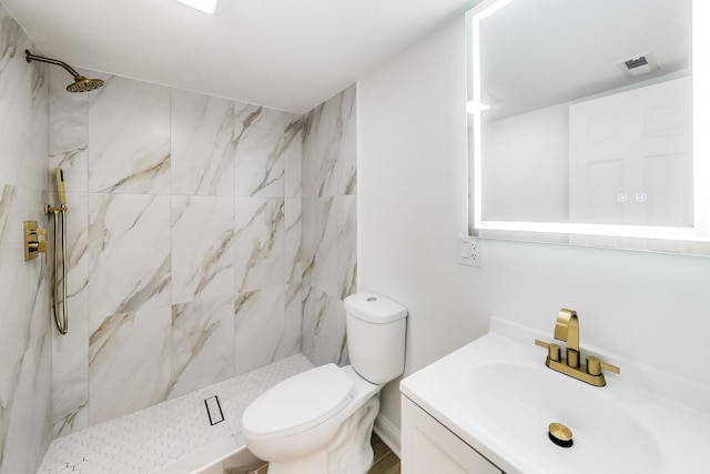 bathroom featuring vanity, toilet, and a tile shower