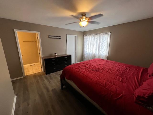 bedroom featuring dark hardwood / wood-style flooring, ceiling fan, and ensuite bathroom