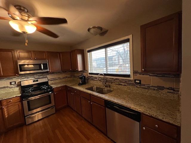 kitchen with tasteful backsplash, light stone countertops, appliances with stainless steel finishes, and sink