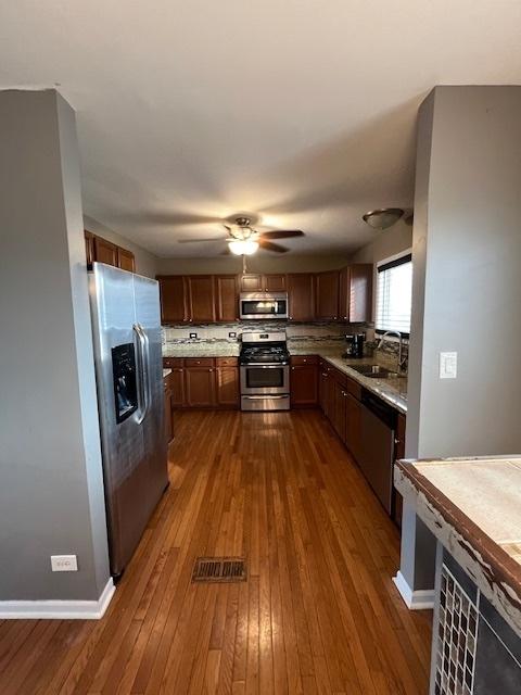 kitchen with sink, ceiling fan, appliances with stainless steel finishes, backsplash, and dark hardwood / wood-style floors