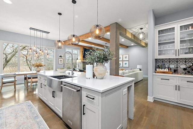 kitchen with white cabinetry, stainless steel dishwasher, decorative light fixtures, and a kitchen island with sink