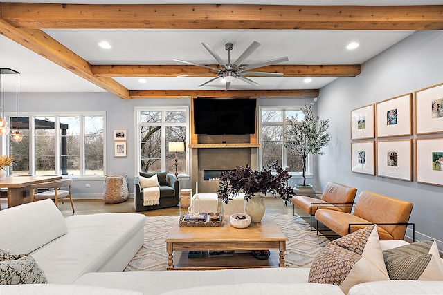 living room with beamed ceiling, ceiling fan, light hardwood / wood-style floors, and a wealth of natural light