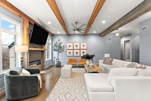 living room featuring ceiling fan, hardwood / wood-style flooring, and beamed ceiling