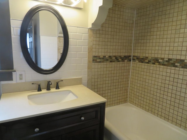 bathroom with vanity, tiled shower / bath, and tile walls