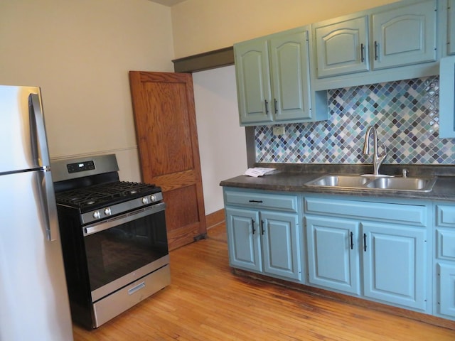 kitchen with tasteful backsplash, sink, fridge, light hardwood / wood-style floors, and gas range