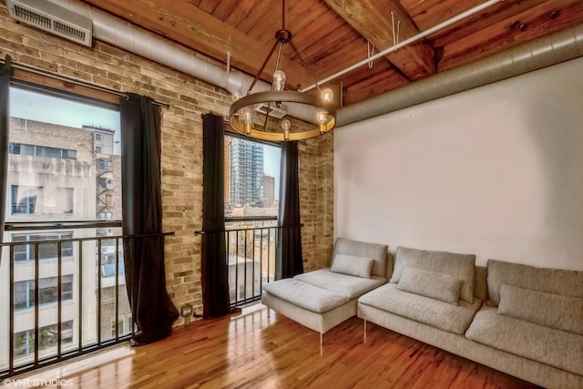 sitting room featuring beamed ceiling, wood-type flooring, brick wall, and wooden ceiling