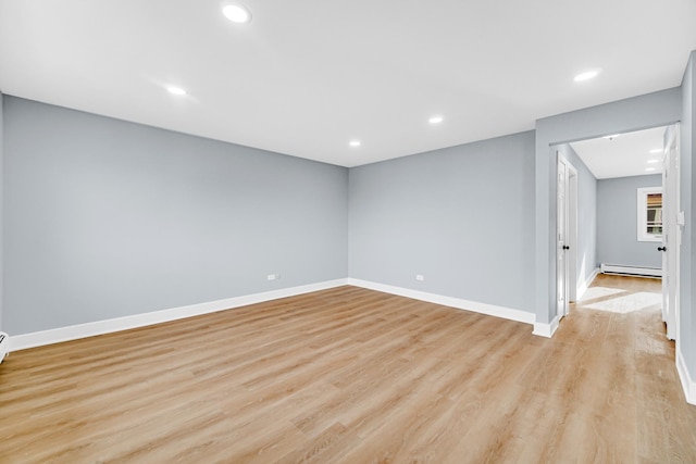 unfurnished room featuring a baseboard heating unit and light hardwood / wood-style flooring