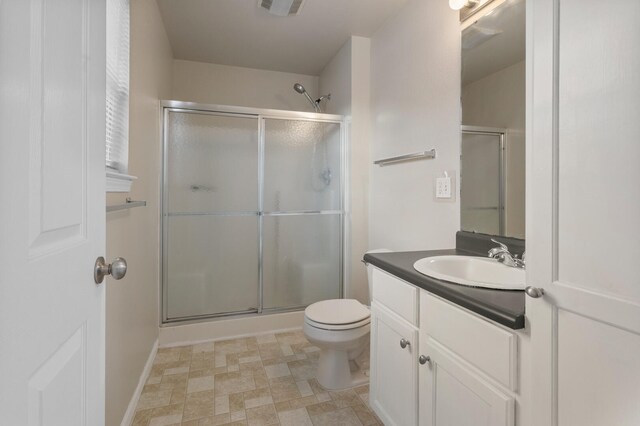 bathroom featuring vanity, a shower with door, and toilet