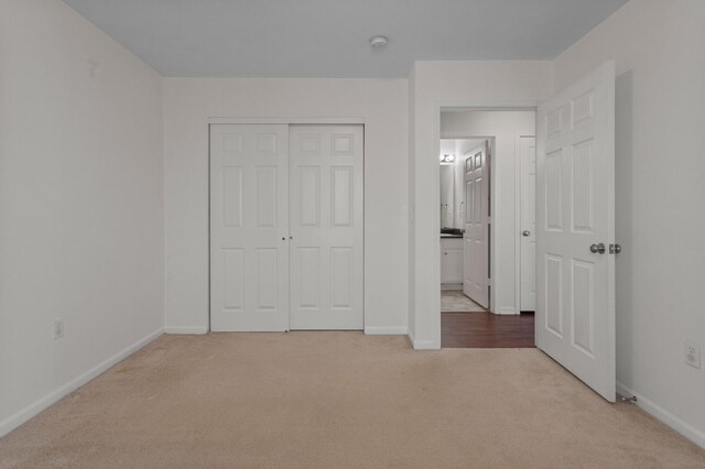unfurnished bedroom with light carpet and a closet