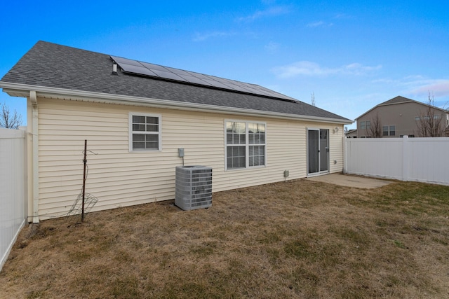 back of house with a yard, cooling unit, and solar panels