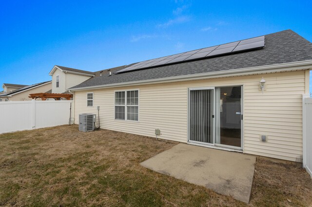 rear view of house featuring central AC, a lawn, and solar panels