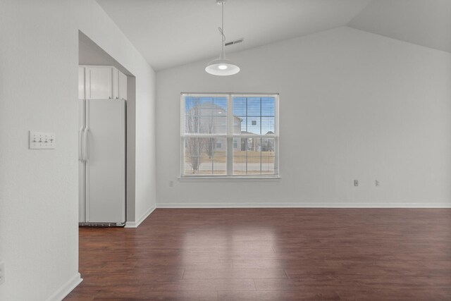 unfurnished dining area featuring vaulted ceiling and dark hardwood / wood-style flooring