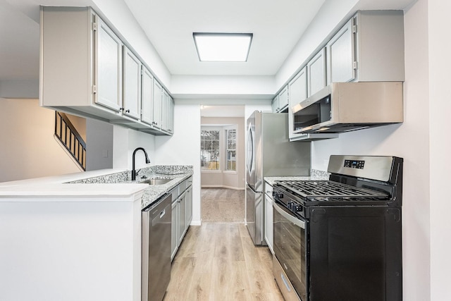 kitchen with stainless steel appliances, sink, gray cabinetry, and light wood-type flooring