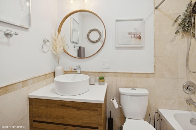 full bathroom featuring tiled shower / bath, vanity, toilet, and tile walls