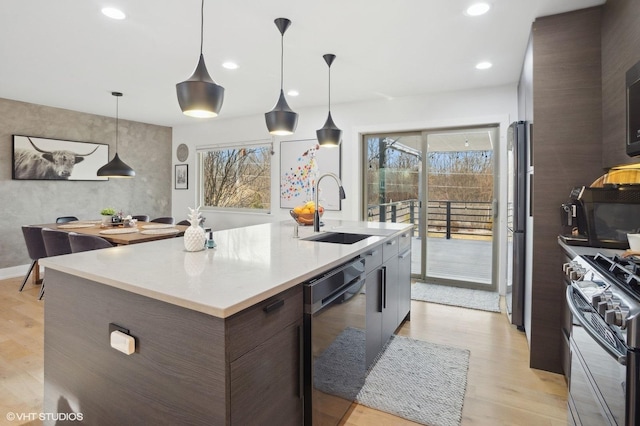 kitchen with pendant lighting, an island with sink, stainless steel appliances, and sink