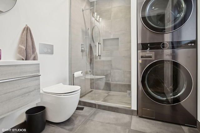 bathroom featuring stacked washer and dryer, tile patterned floors, toilet, and a shower with shower door