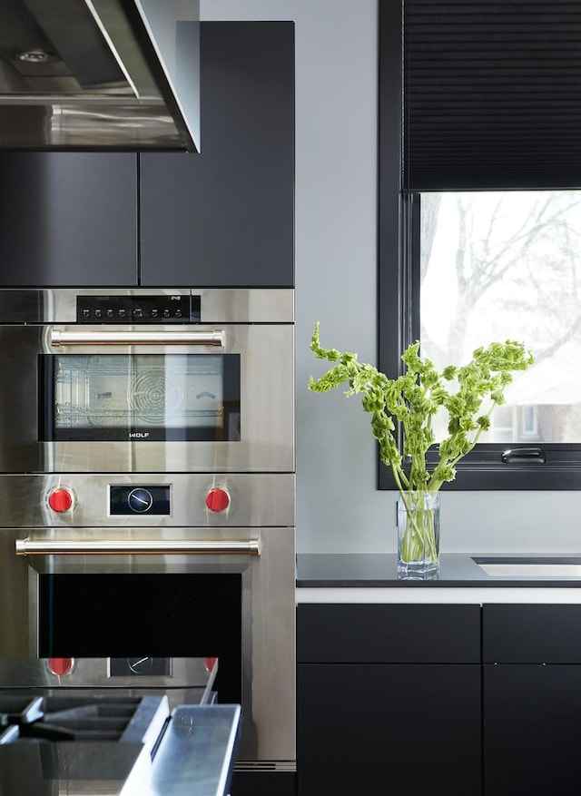 6505 N Knox Ave, Lincolnwood, IL 60645 - kitchen featuring range hood, modern cabinets, dark cabinetry, and stainless steel double oven