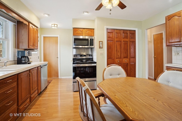 kitchen featuring appliances with stainless steel finishes, tasteful backsplash, sink, ceiling fan, and light hardwood / wood-style floors