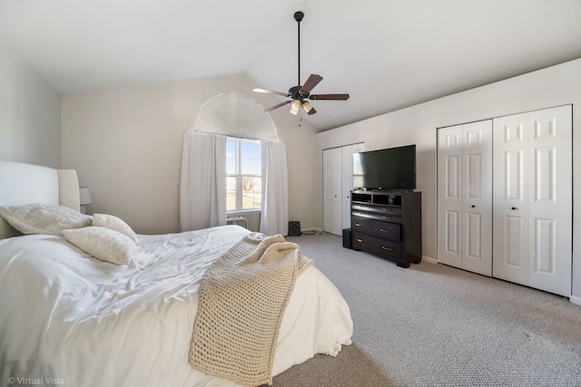 bedroom featuring lofted ceiling, two closets, light colored carpet, and ceiling fan