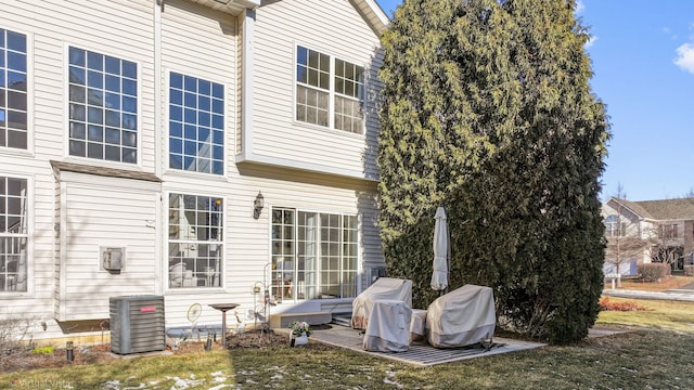 rear view of house featuring central AC unit and a yard