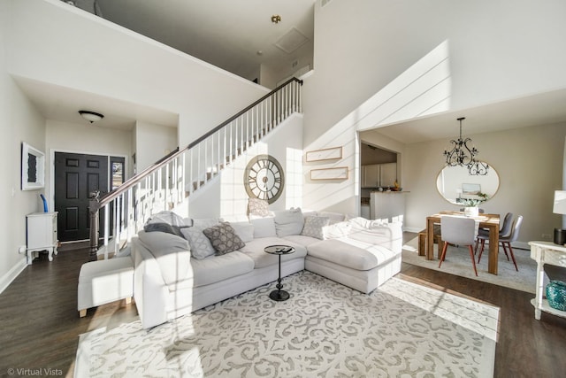 living room featuring hardwood / wood-style flooring, a towering ceiling, and an inviting chandelier