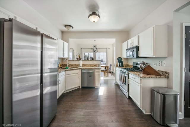 kitchen featuring stone countertops, decorative light fixtures, white cabinets, kitchen peninsula, and stainless steel appliances