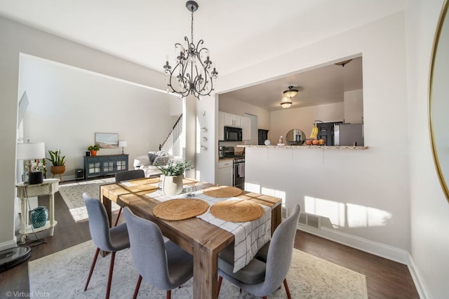 dining space featuring dark wood-type flooring and an inviting chandelier