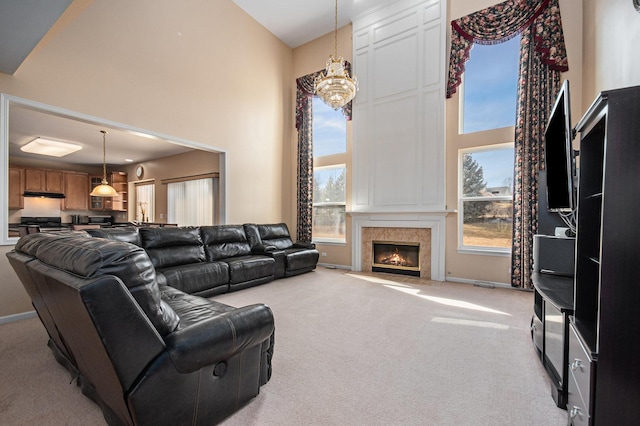 carpeted living room featuring a high ceiling, a wealth of natural light, a notable chandelier, and a fireplace