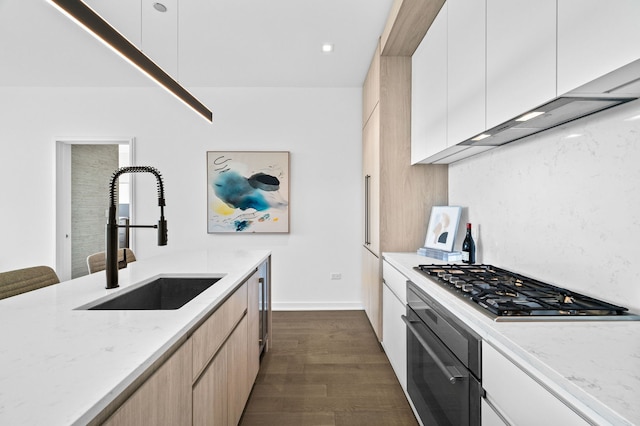 kitchen with light stone counters, stainless steel gas cooktop, dark wood-type flooring, a sink, and oven