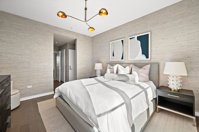 bedroom featuring a chandelier, wood-type flooring, and baseboards