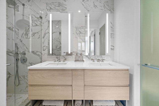 bathroom featuring double vanity, a marble finish shower, tile walls, and a sink