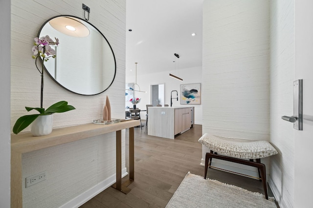 hallway with a towering ceiling and wood finished floors