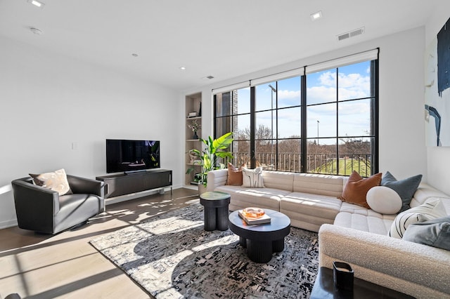 living room featuring built in shelves, recessed lighting, visible vents, wood finished floors, and baseboards