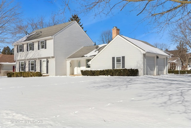 snow covered property featuring a garage and a chimney