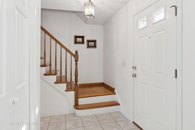 entryway featuring stairway, baseboards, an inviting chandelier, and light tile patterned floors