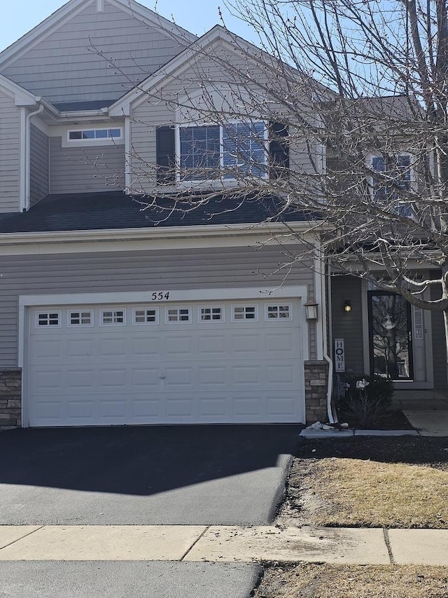 view of front of property featuring aphalt driveway, stone siding, and a garage