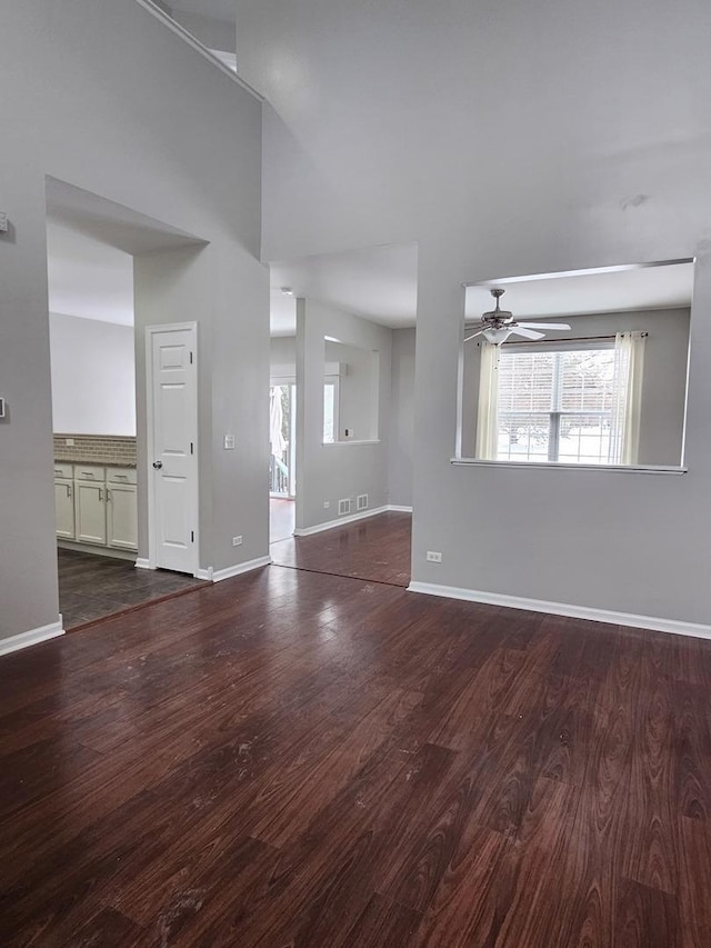 unfurnished living room with ceiling fan, wood finished floors, and baseboards