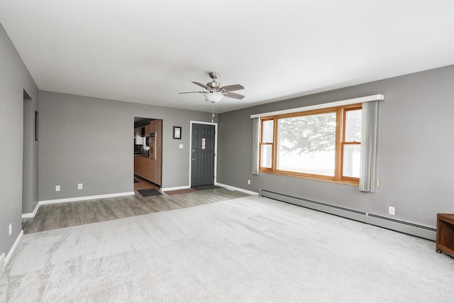 spare room featuring baseboards, ceiling fan, light wood finished floors, and baseboard heating